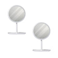 Two white round smart LED makeup vanity mirrors with adjustable tricolor lights on a bedroom table