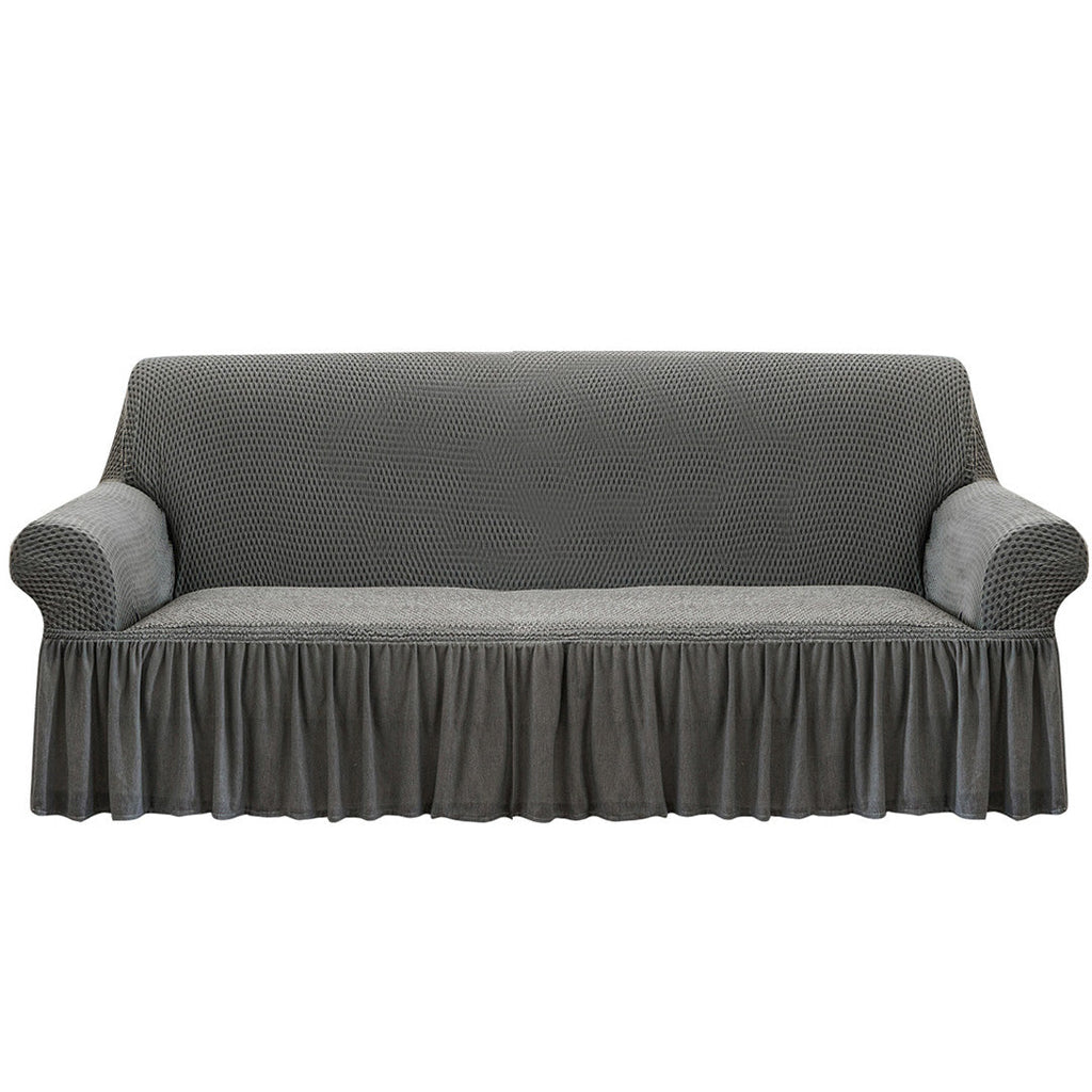 4-seater grey stretch sofa cover with ruffled skirt on a living room couch