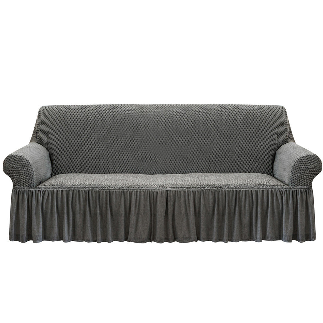4-seater grey stretch sofa cover with ruffled skirt on a living room couch