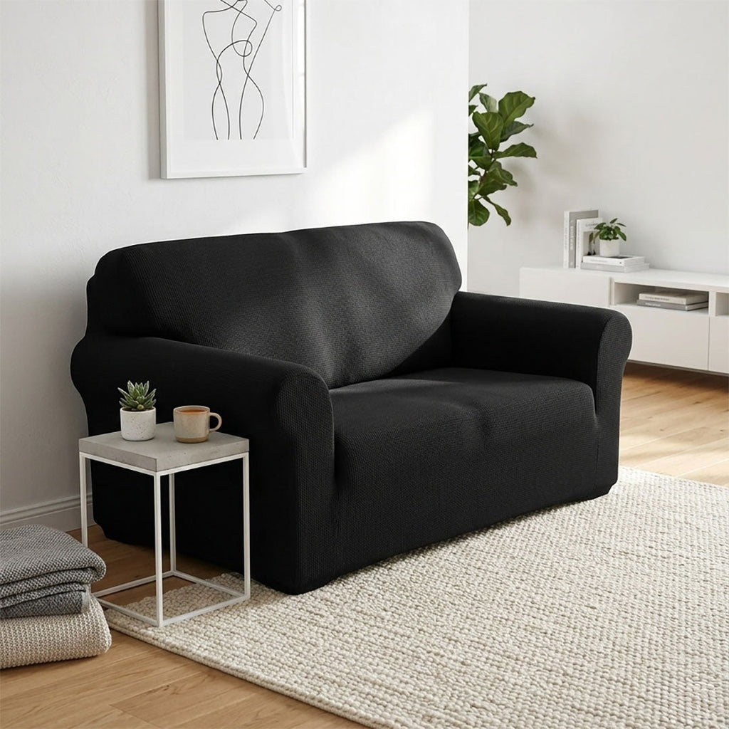 Black 2-seater high stretch sofa cover protecting a living room couch from spills and stains — view 3