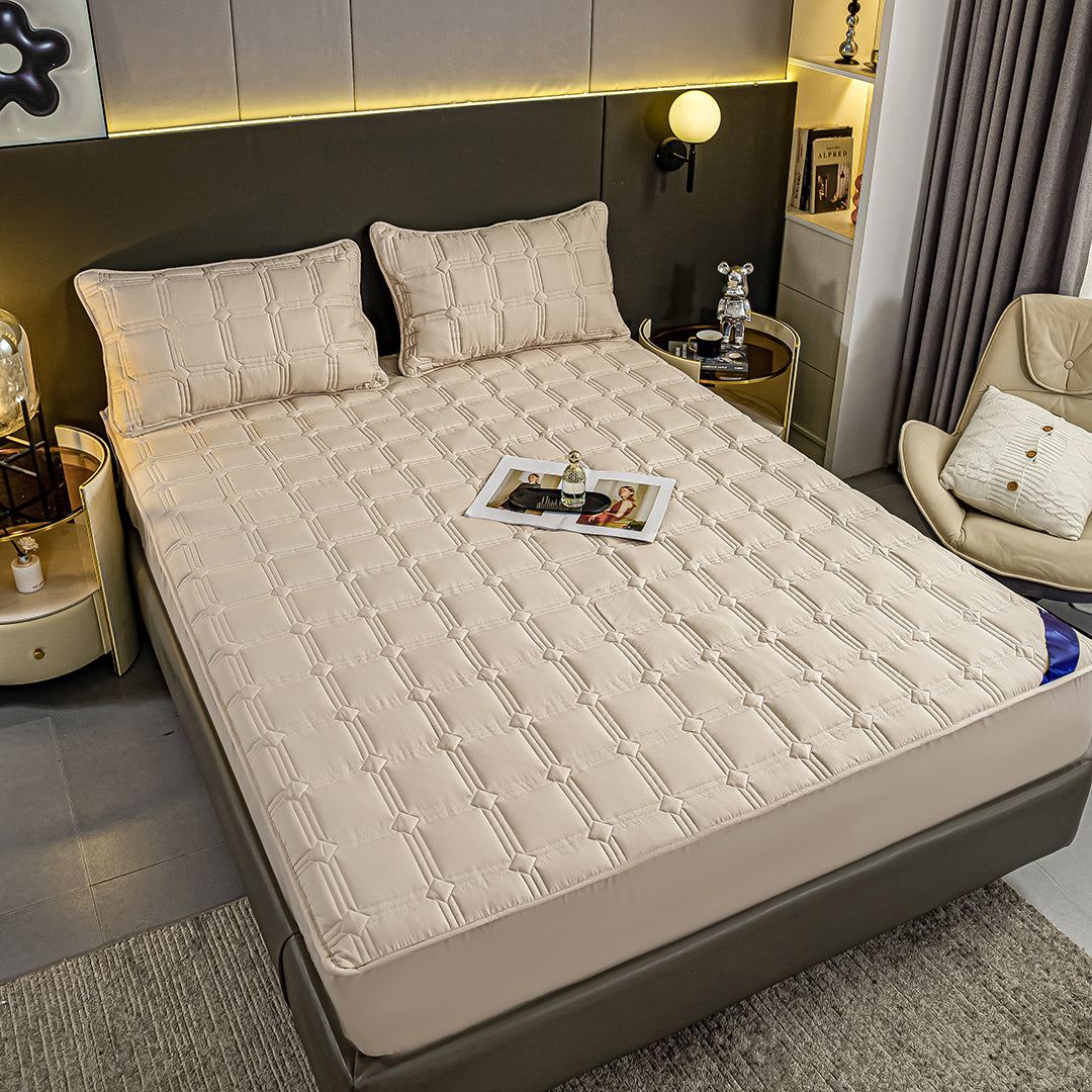 Beige quilted stretchable mattress cover and two matching pillow cases displayed on a bed. — view 4