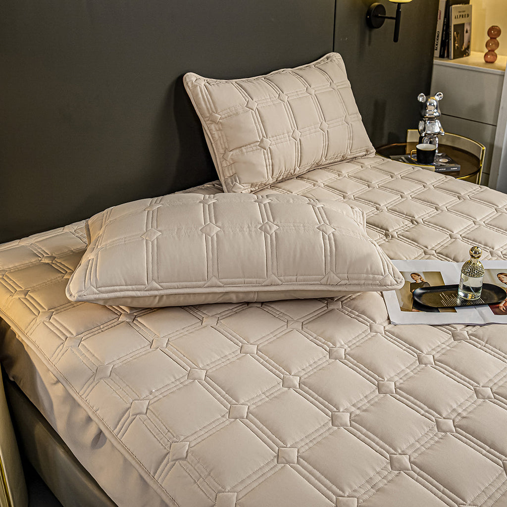 Beige quilted stretchable mattress cover and two matching pillow cases displayed on a bed. — view 5