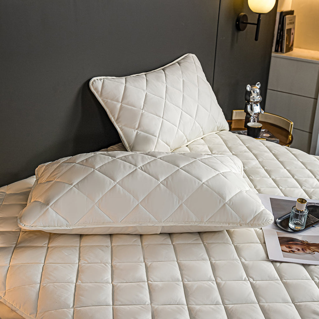 White quilted mattress cover and two matching pillow protectors displayed on a well-made comfortable bed — view 5