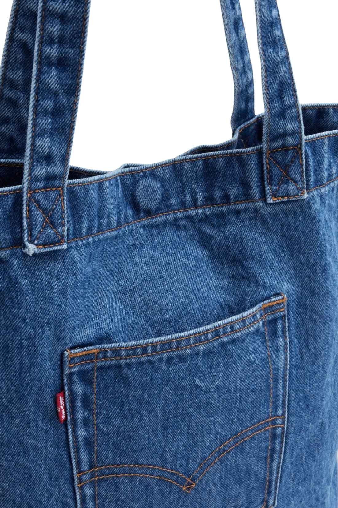 Beige denim tote bag with double handles, snap fastening, front pocket, and red signature label — view 9