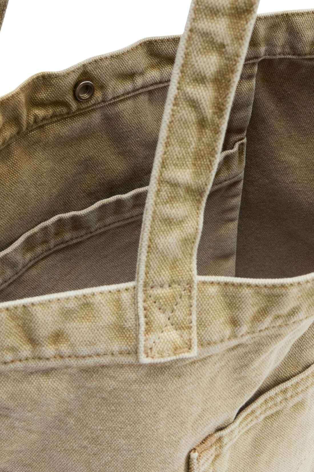 Beige denim tote bag with double handles, snap fastening, front pocket, and red signature label — view 25