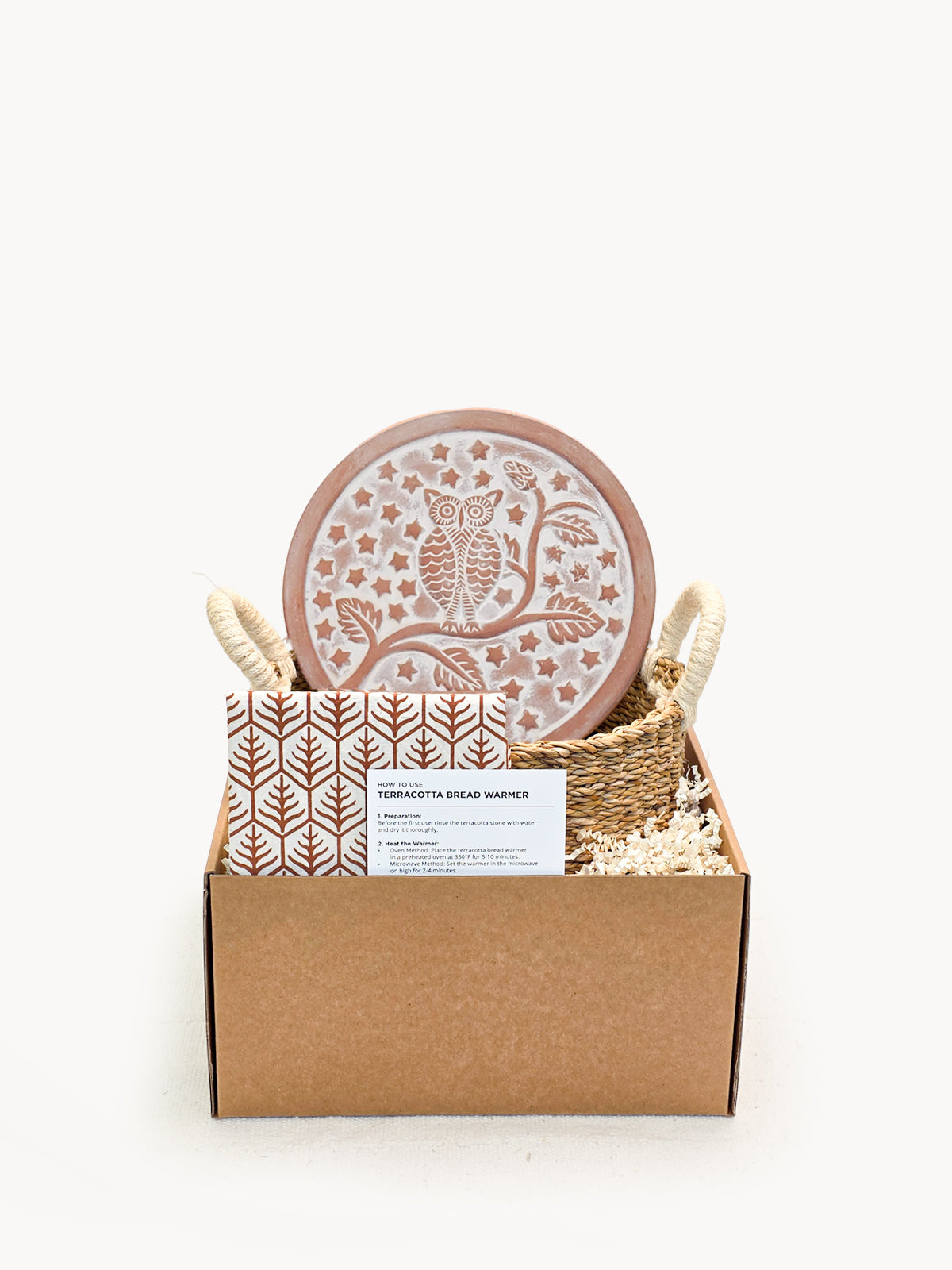 Owl terracotta bread warmer stone in a woven seagrass basket with a printed cotton tea towel