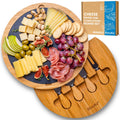 Round bamboo cheese board with removable slate, hidden drawer, and four stainless steel serving knives.