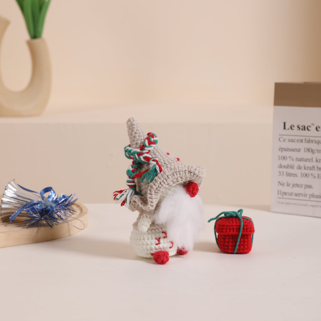 Complete Christmas gnome amigurumi DIY crochet kit with white hat, yarn, hook, and instructions.