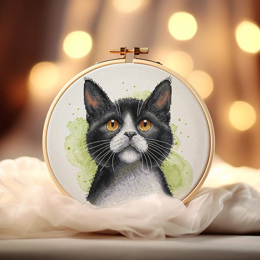 Tuxedo cat cross stitch pattern design featuring a black and white kitten portrait