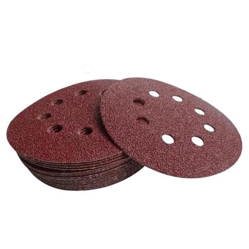 5-inch orbital sanding discs with 8 holes in assorted grits arranged on a flat surface — view 2