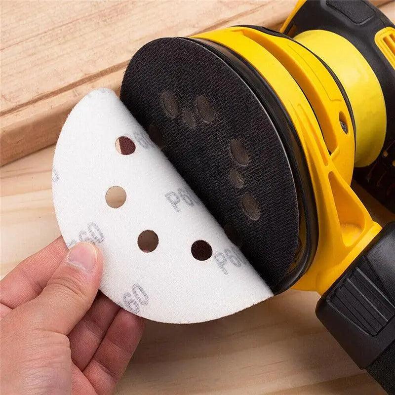 5-inch orbital sanding discs with 8 holes in assorted grits arranged on a flat surface — view 3