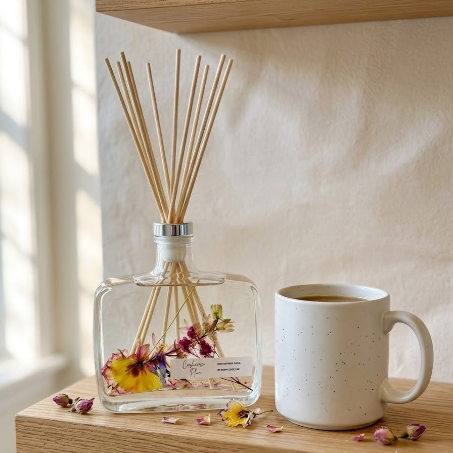 Handmade botanical reed diffuser in a clear minimalist glass bottle with natural rattan reeds
