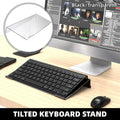 Transparent tilted acrylic keyboard stand supporting a compact black mechanical keyboard on a desk