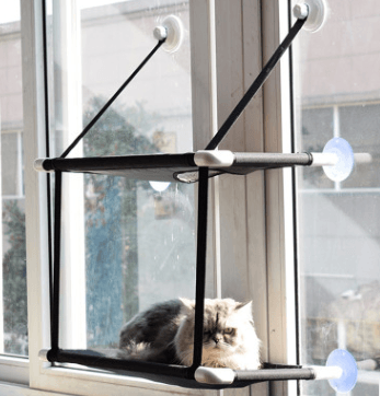 Window sill cat hammock in neutral coral velvet mounted to a glass window with suction cups