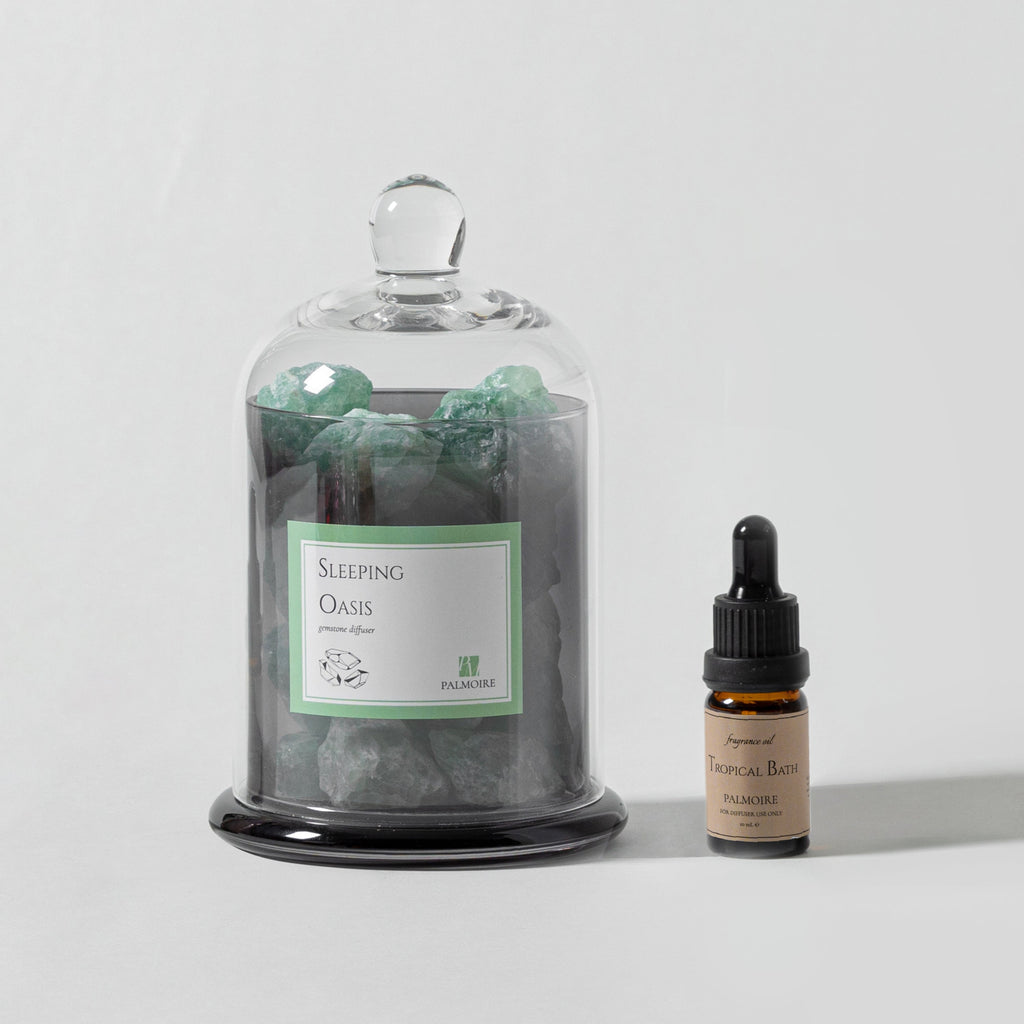 Sleeping Oasis gemstone diffuser with natural stones and Tropical Bath fragrance oil bottle.