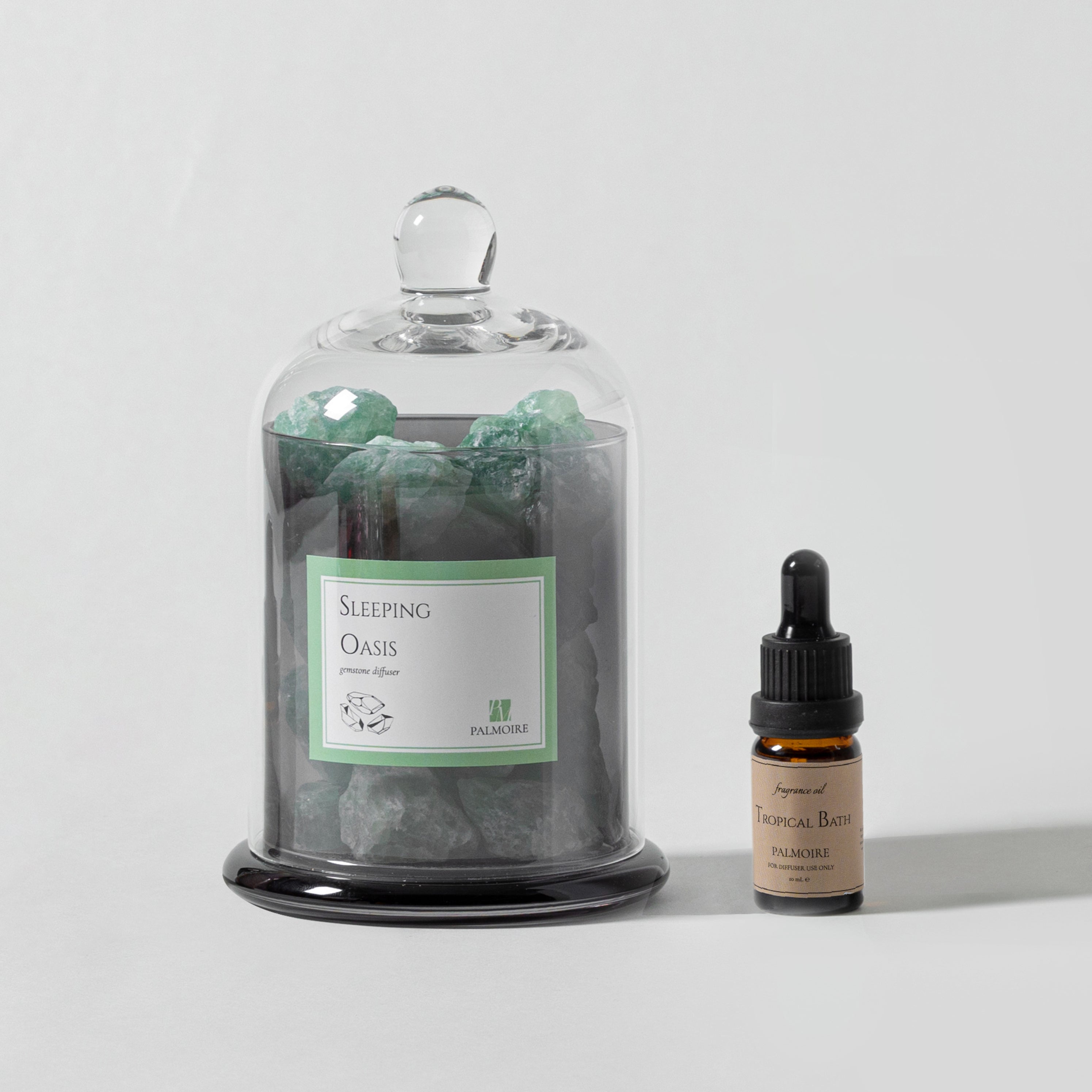 Sleeping Oasis gemstone diffuser with natural stones and Tropical Bath fragrance oil bottle.