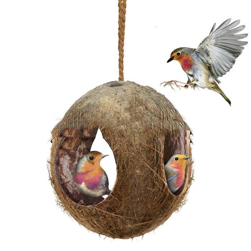 Rustic natural coconut shell bird nest feeder hanging from a garden branch outdoors — view 2
