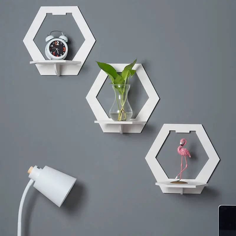 Set of 3 glossy white hexagonal floating wall shelves displaying small plants and picture frames — view 4