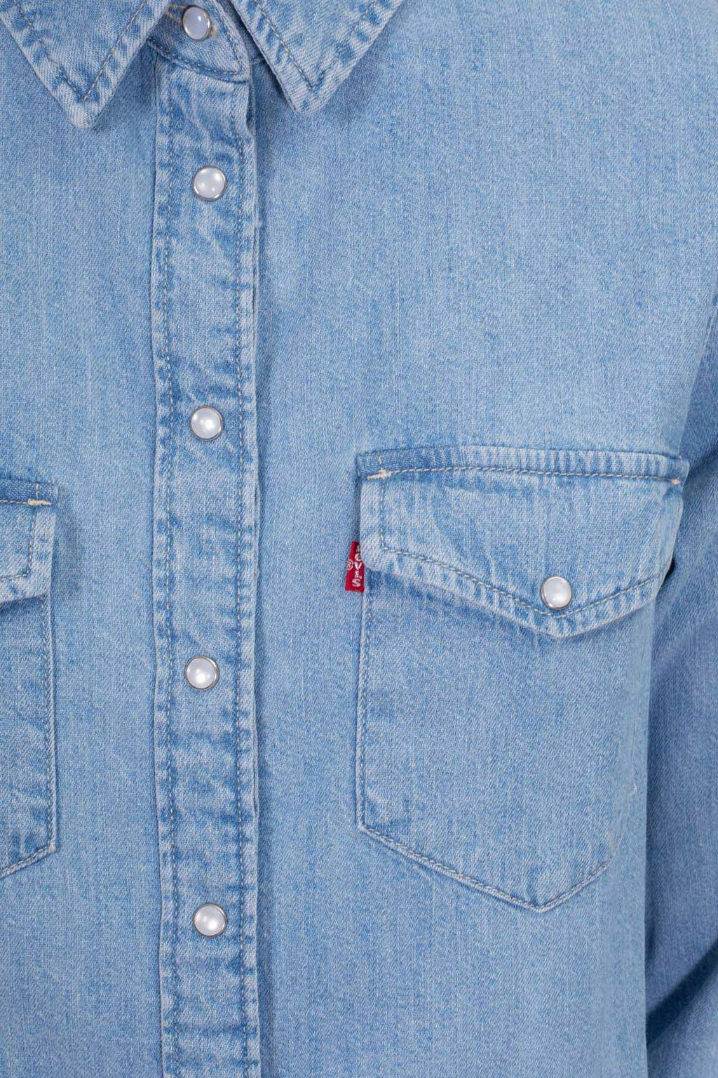 Women's light blue wash denim shirt with snap buttons, long sleeves, and front flap pockets.