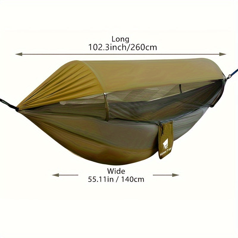 Green nylon double camping hammock with mosquito net hanging between two trees in a forest — view 3