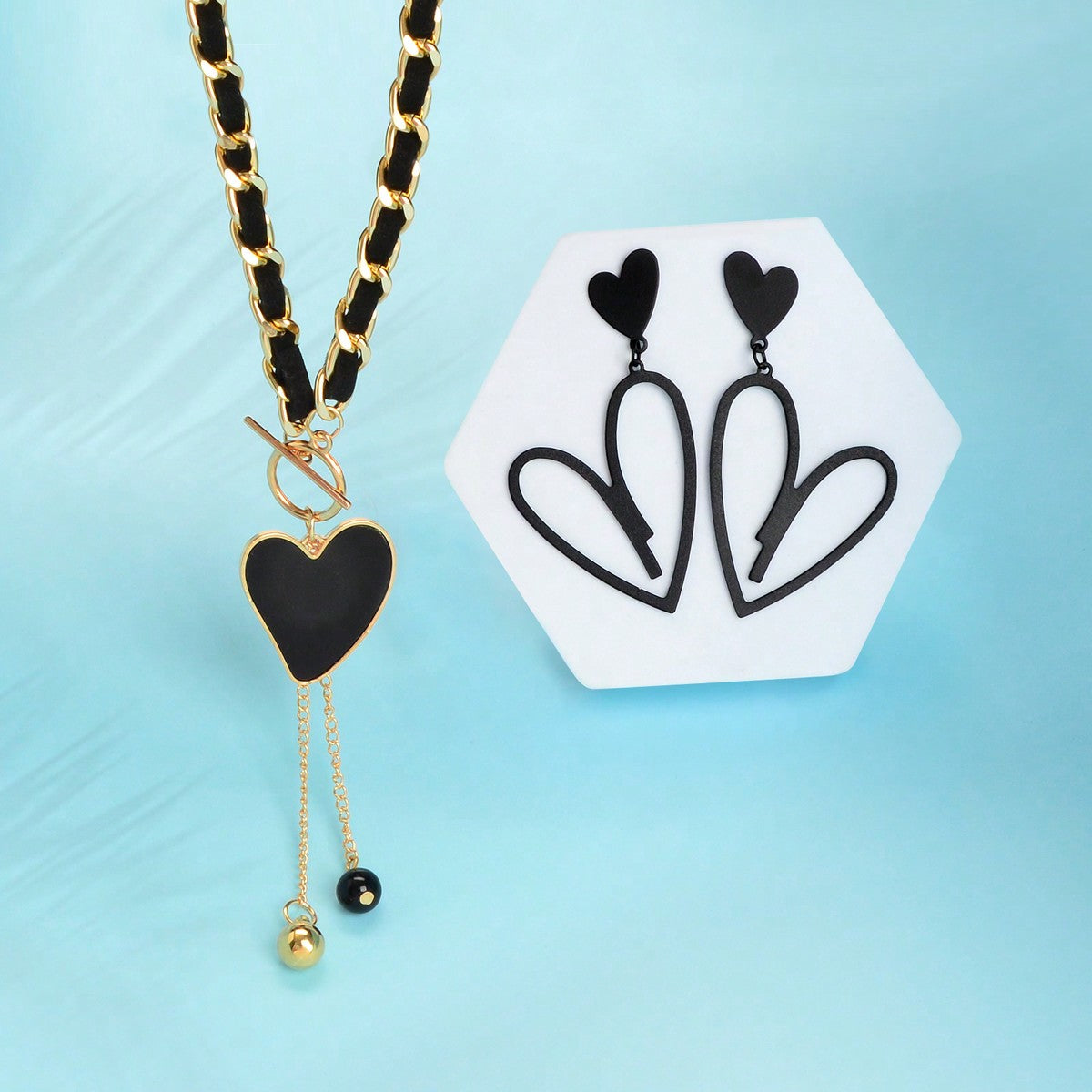 Black heart pendant necklace and matching earrings set crafted from polished metal with dark centerpieces.