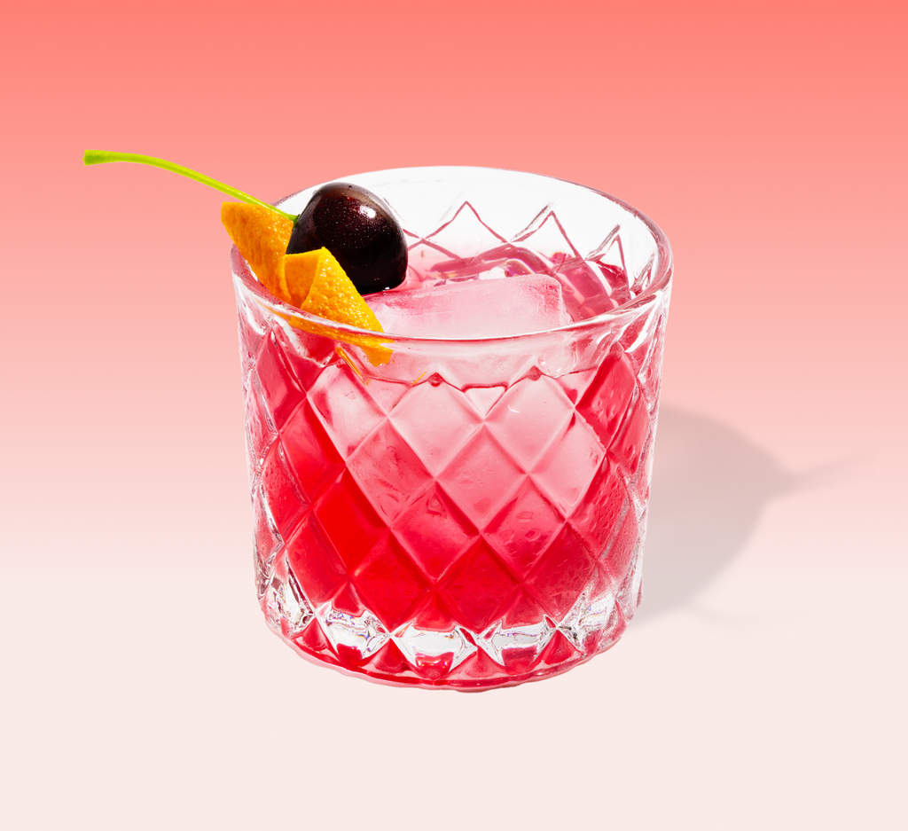 Black cherry old fashioned cocktail mix packet with a dark red drink over ice — view 2