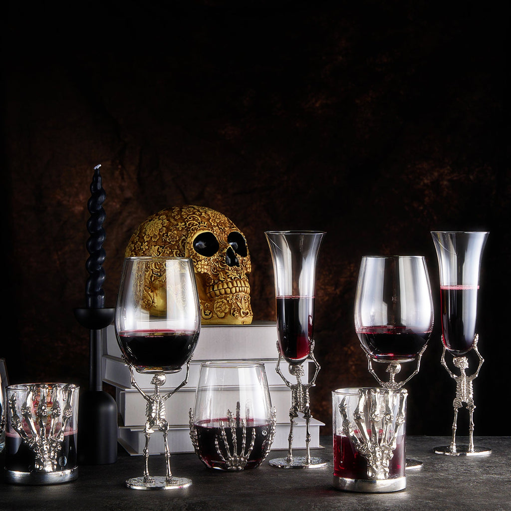 Skeleton whiskey glass tumbler with detailed bone hand stem, clear glass cup holding amber liquor — view 3