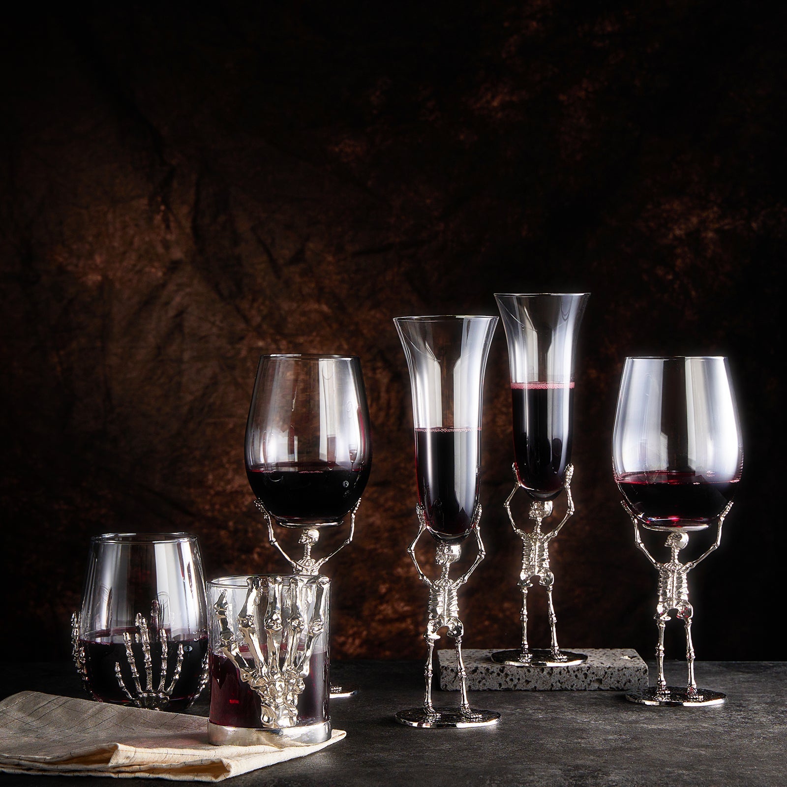 Skeleton whiskey glass tumbler with detailed bone hand stem, clear glass cup holding amber liquor — view 4