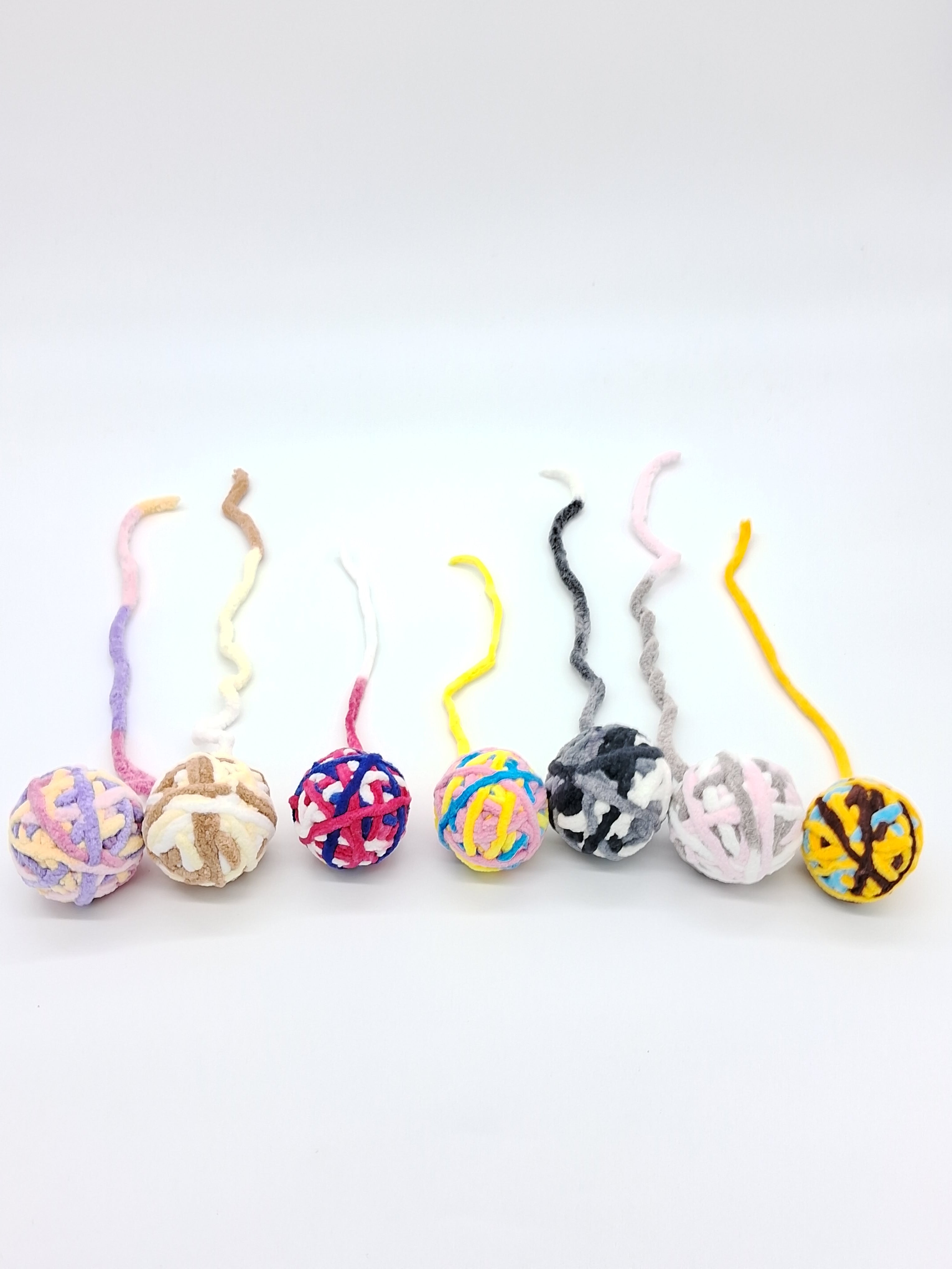 Large textured yarn ball cat toy in assorted colors with an interactive attached string tail — view 2
