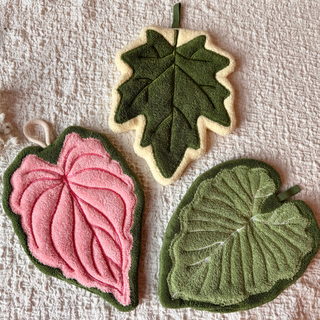 Set of three modern leaf shaped plush hanging hand towels in green, pink, and maple.