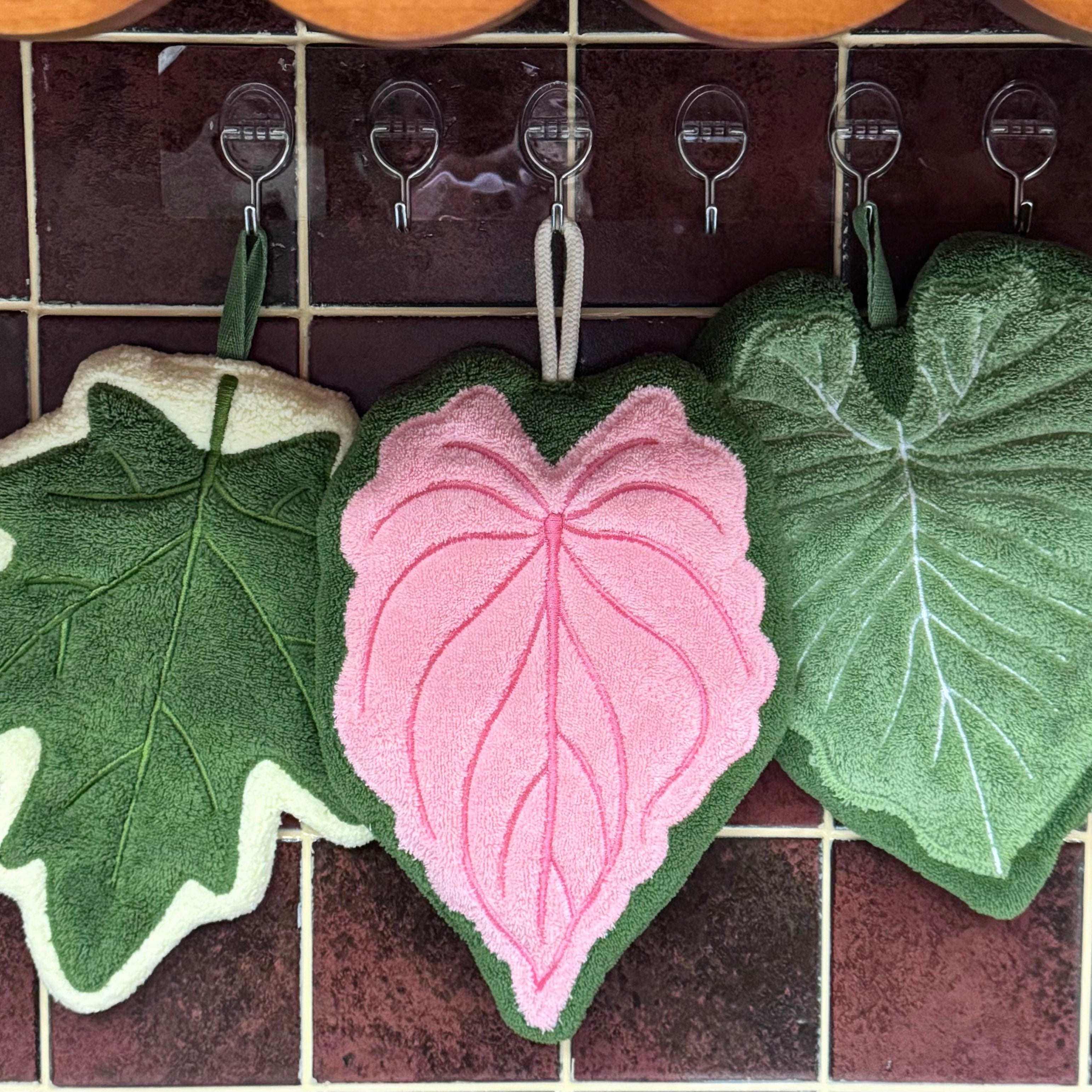 Set of three modern leaf shaped plush hanging hand towels in green, pink, and maple. — view 3