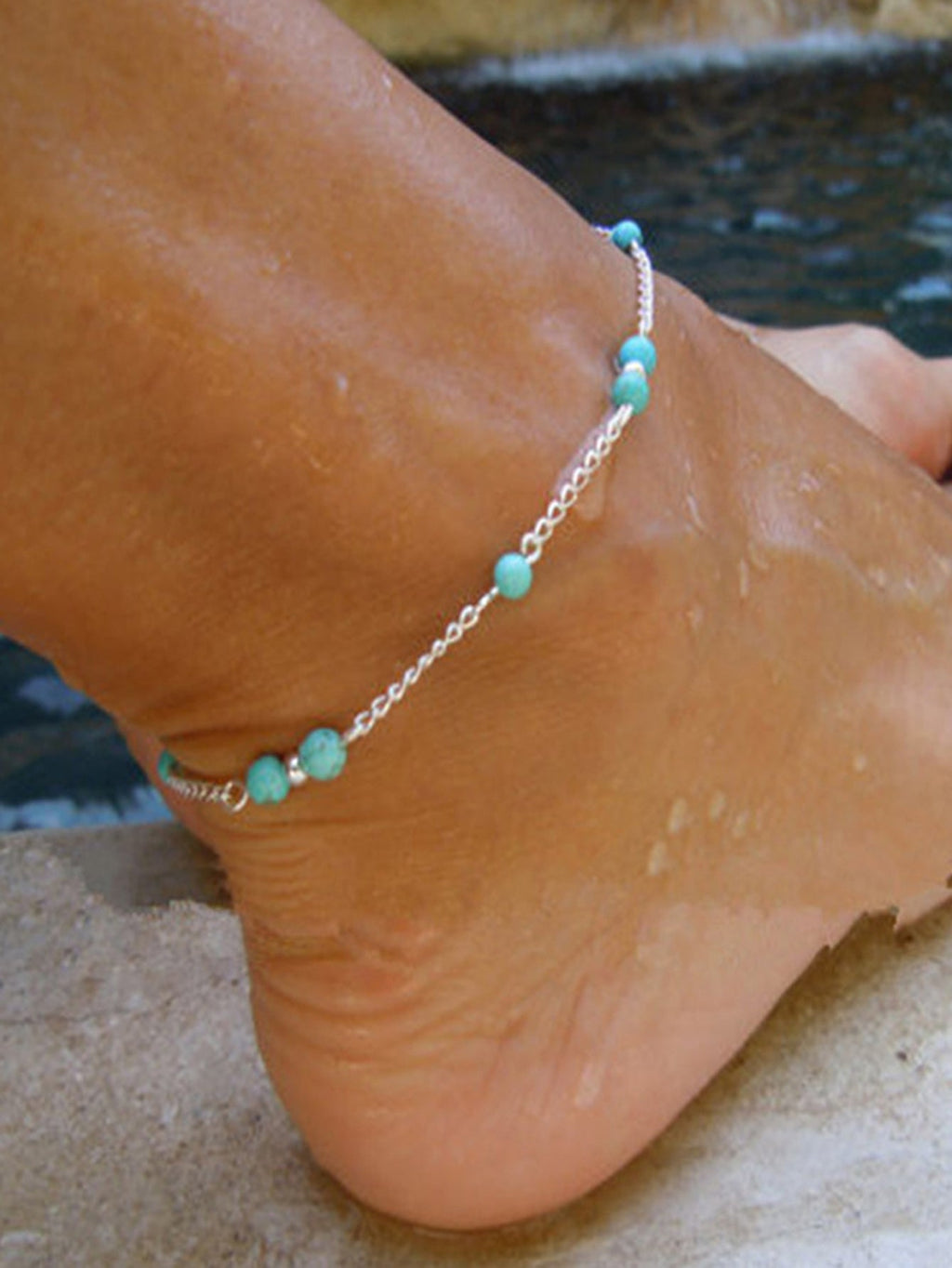 Boho chic turquoise barefoot sandal anklet with delicate silver chains draped gracefully over a foot