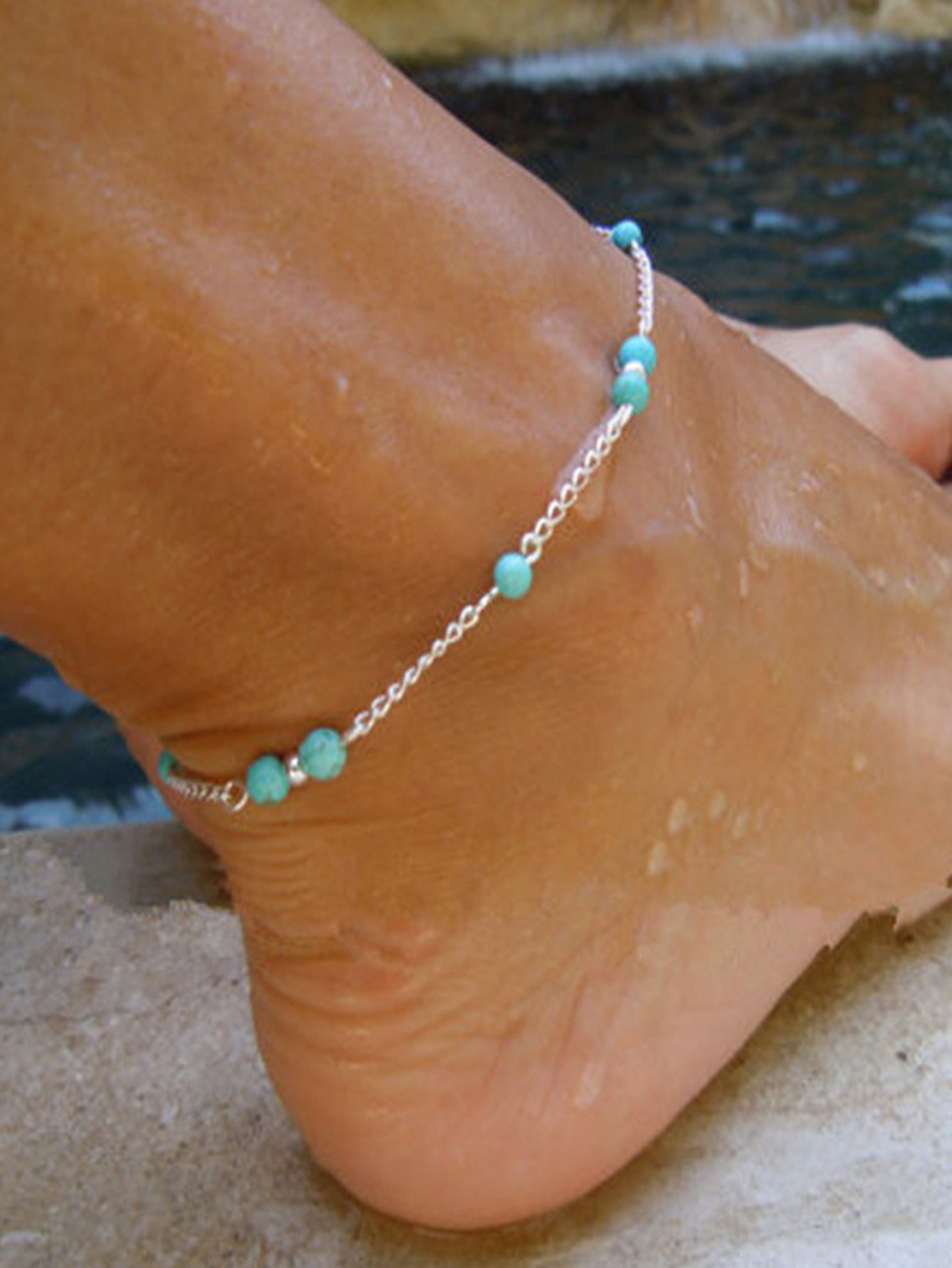 Boho chic turquoise barefoot sandal anklet with delicate silver chains draped gracefully over a foot