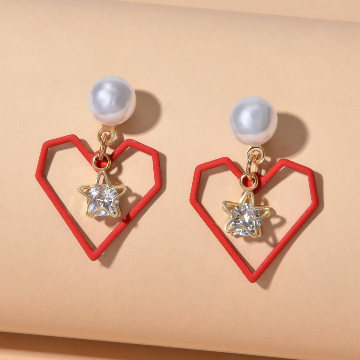 Gold tone dangle earrings featuring rhinestone star and pearl heart decorations on a white background — view 5