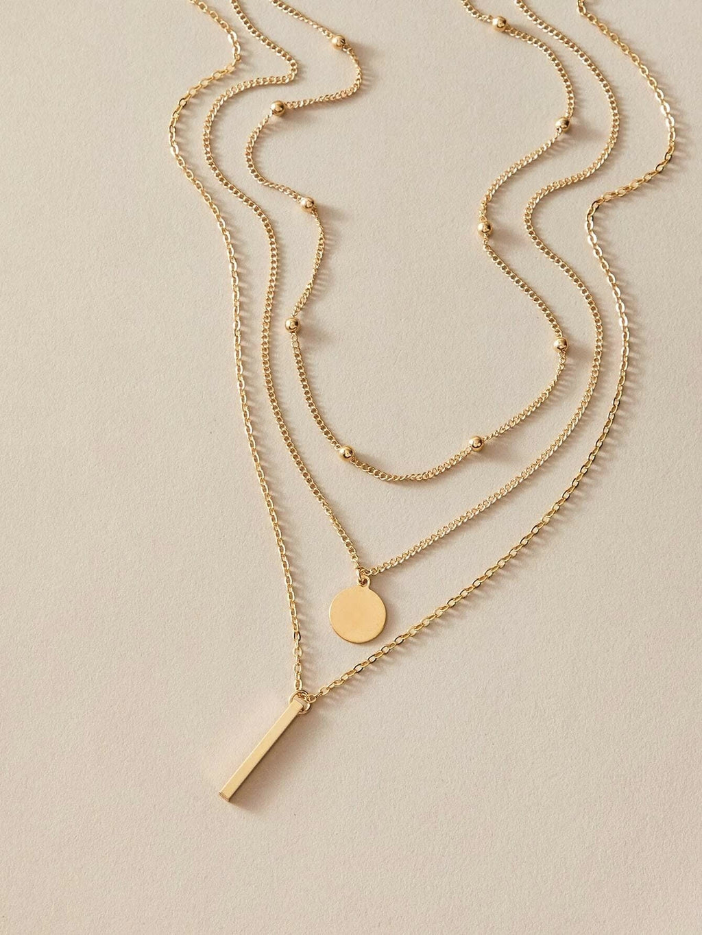 Boho multi-layer charm necklace with bar, disc, and round bead pendants on adjustable metallic chain. — view 2