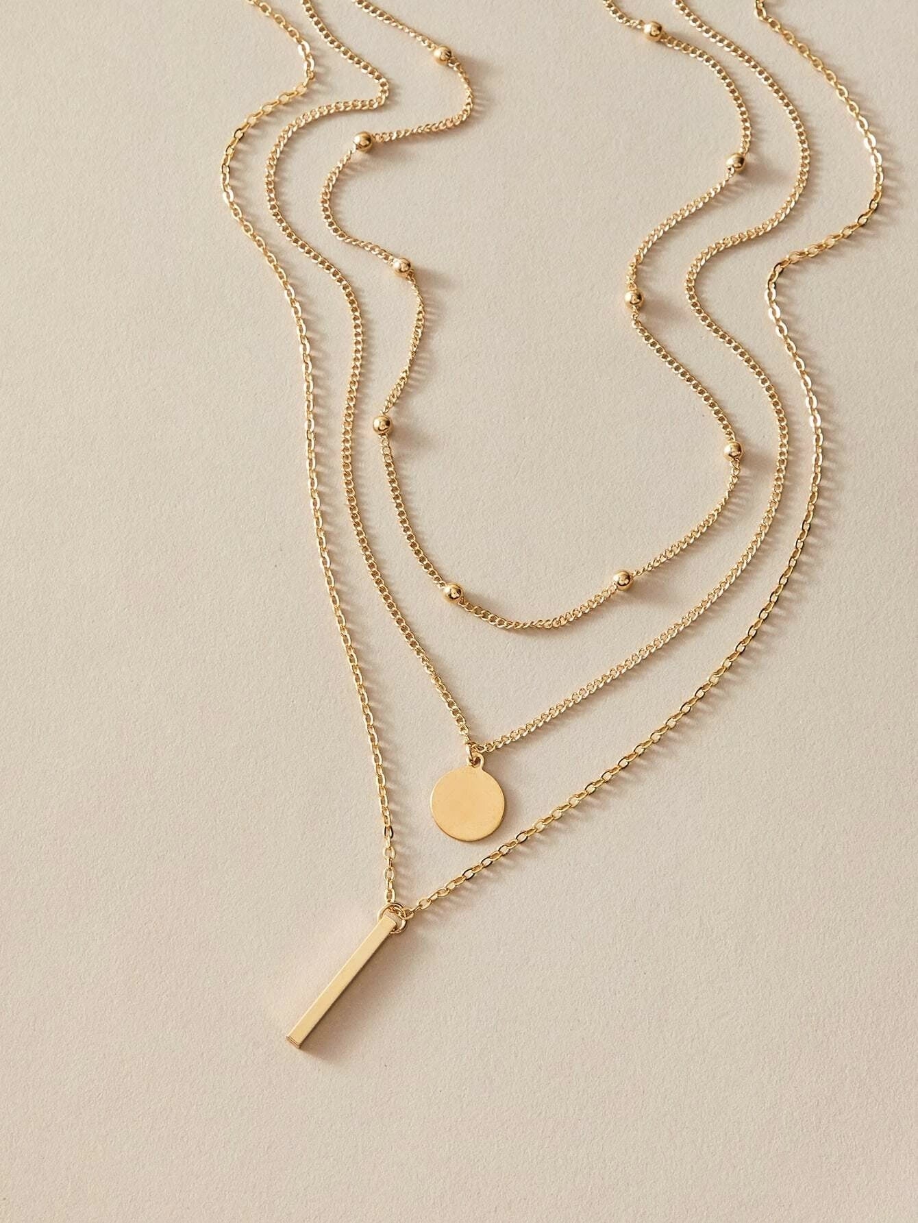 Boho multi-layer charm necklace with bar, disc, and round bead pendants on adjustable metallic chain. — view 2