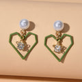 Gold tone dangle earrings featuring rhinestone star and pearl heart decorations on a white background