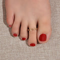 Gold geometric toe and finger ring jewelry piece on a clean white background.