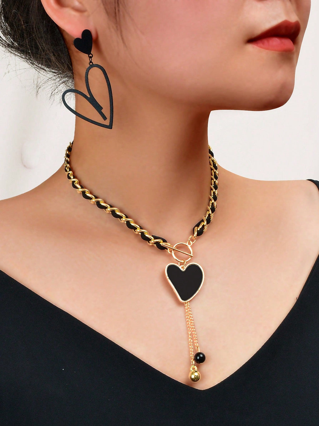 Black heart pendant necklace and matching earrings set crafted from polished metal with dark centerpieces. — view 2