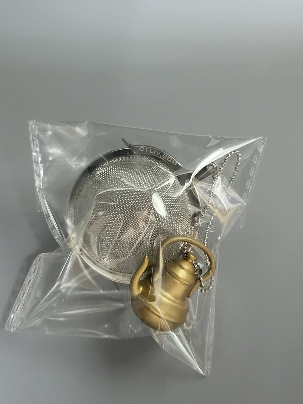 Stainless steel mesh tea infuser ball with a decorative gold teapot charm and metal chain — view 4