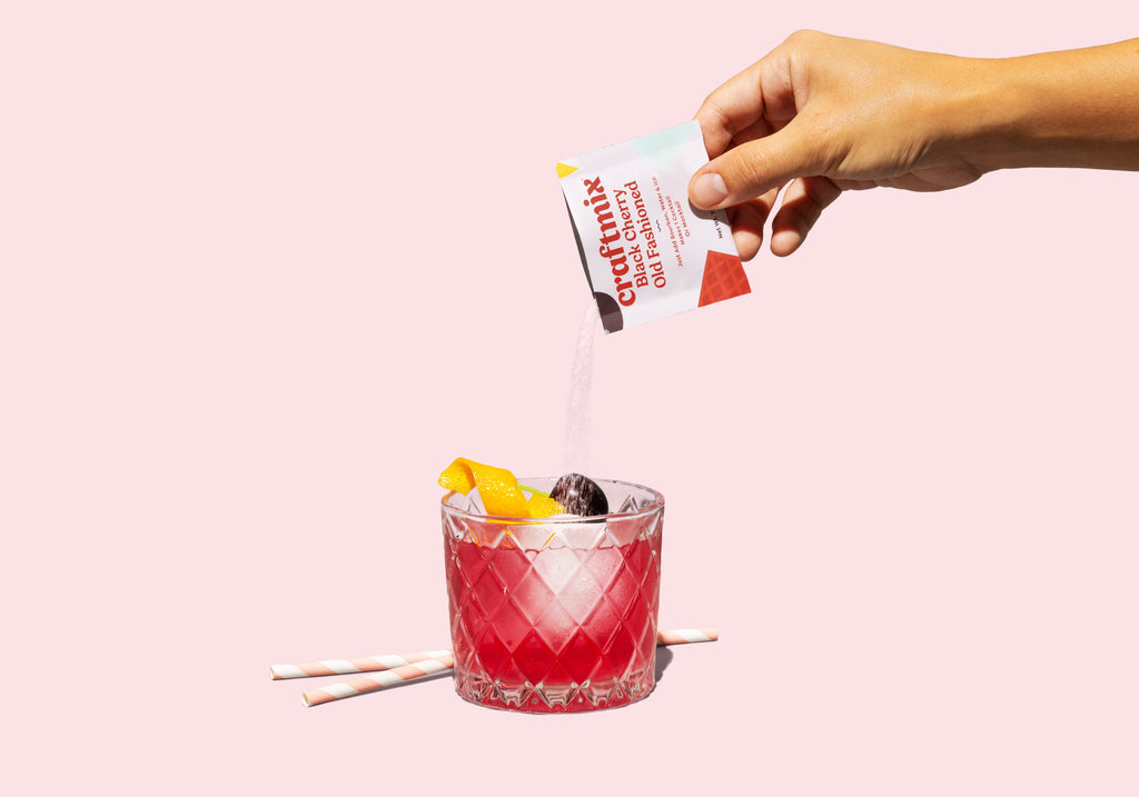 Black cherry old fashioned cocktail mix packet with a dark red drink over ice — view 3