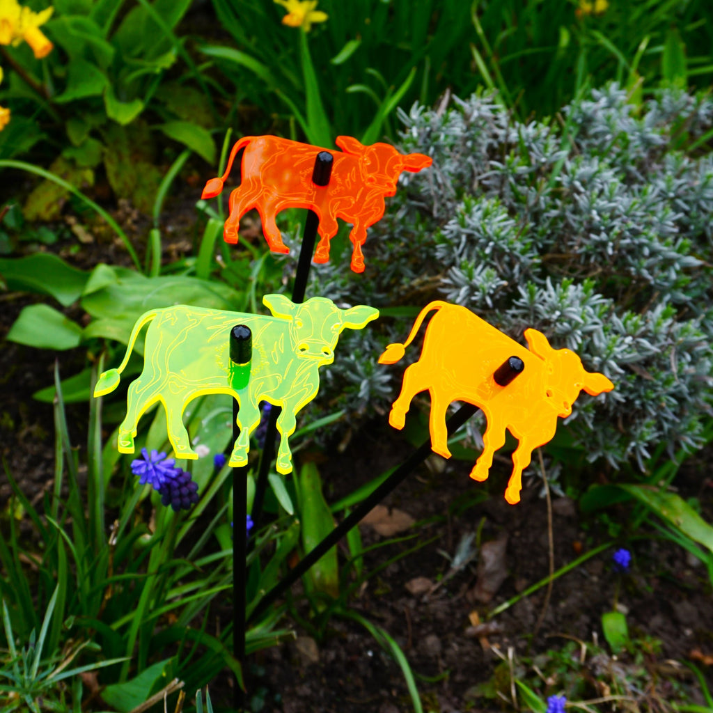 Three glowing cow garden stakes, vibrant suncatcher yard ornaments displayed in a flower bed — view 4