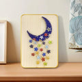 Moon string art craft kit featuring colourful thread, metal pins, and a wooden display stand