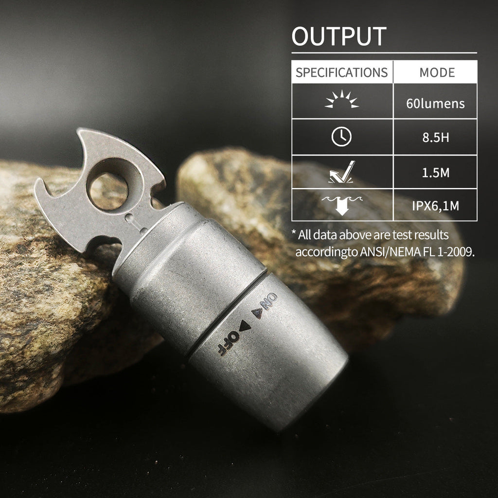 Titanium EDC keychain flashlight with integrated bottle opener attached to metal keyring on plain background — view 2