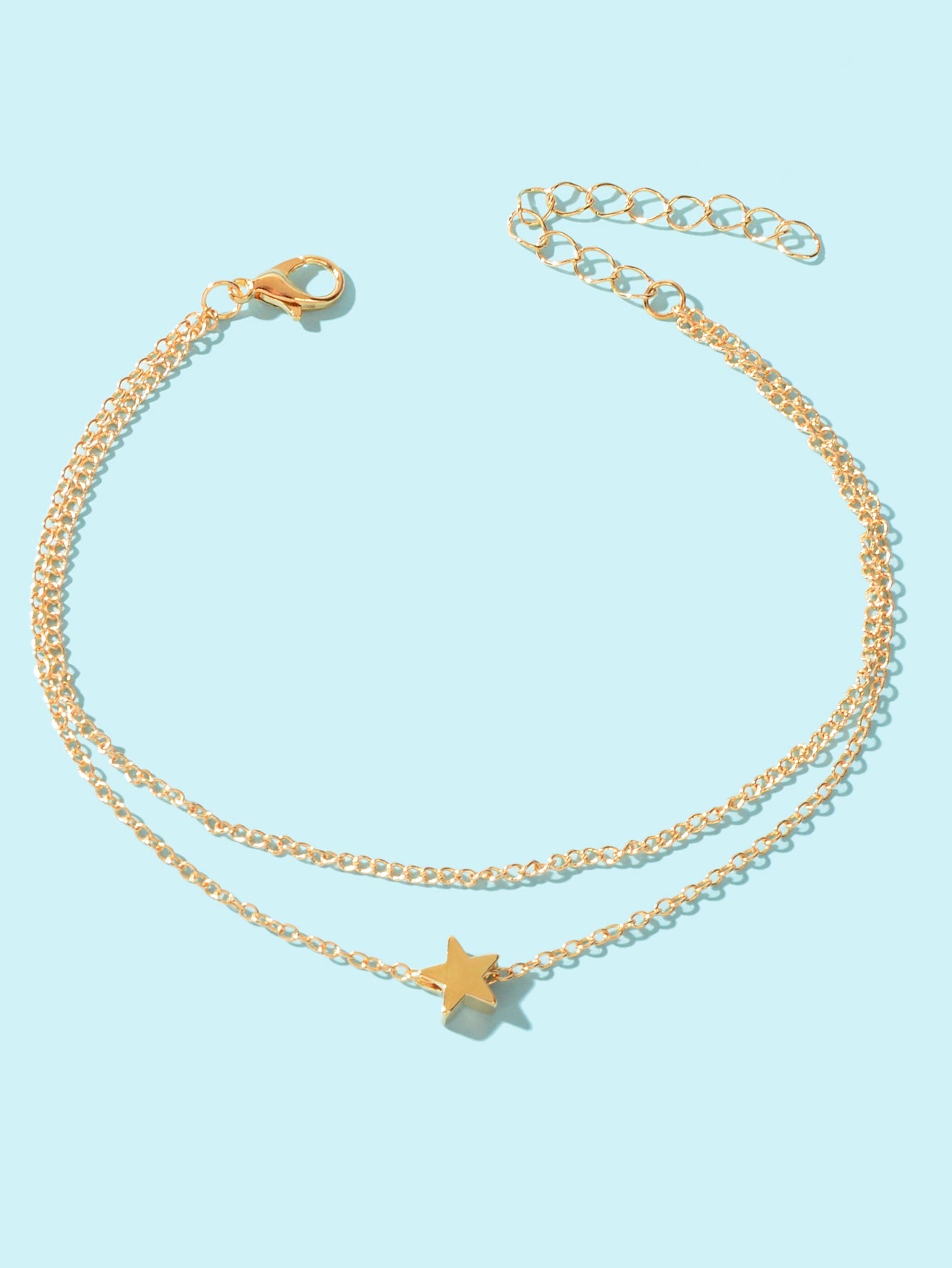 Minimalist double layered gold chain anklet featuring delicate star charms on a plain background — view 2