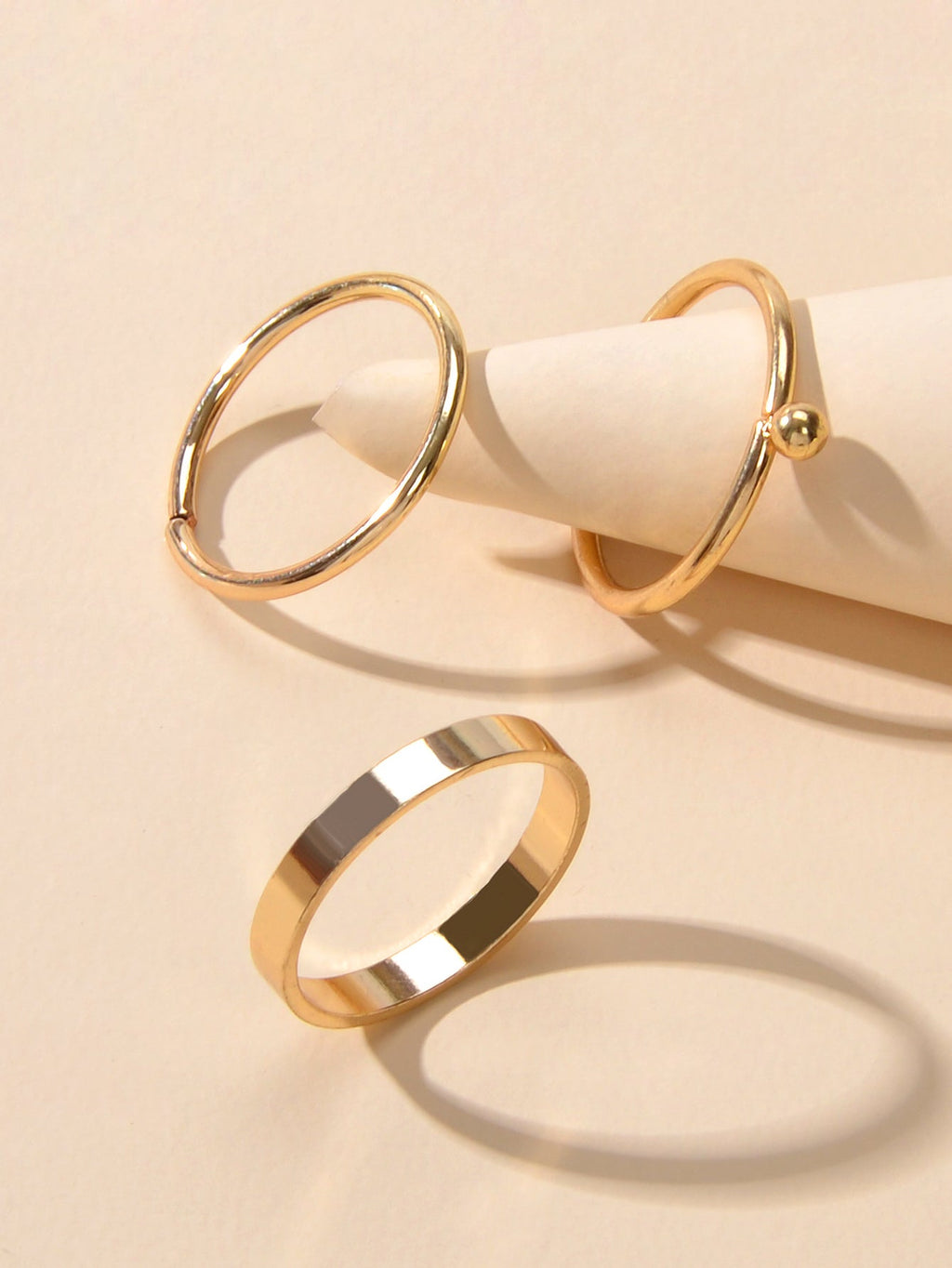 Minimalist gold stackable ring set featuring three polished metal bands arranged gracefully together — view 2