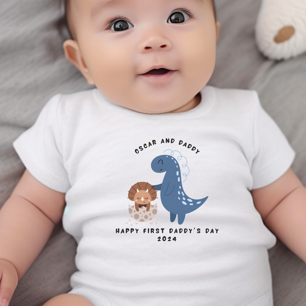 Personalised first fathers day dinosaur baby outfit in white cotton presented in a gift box
