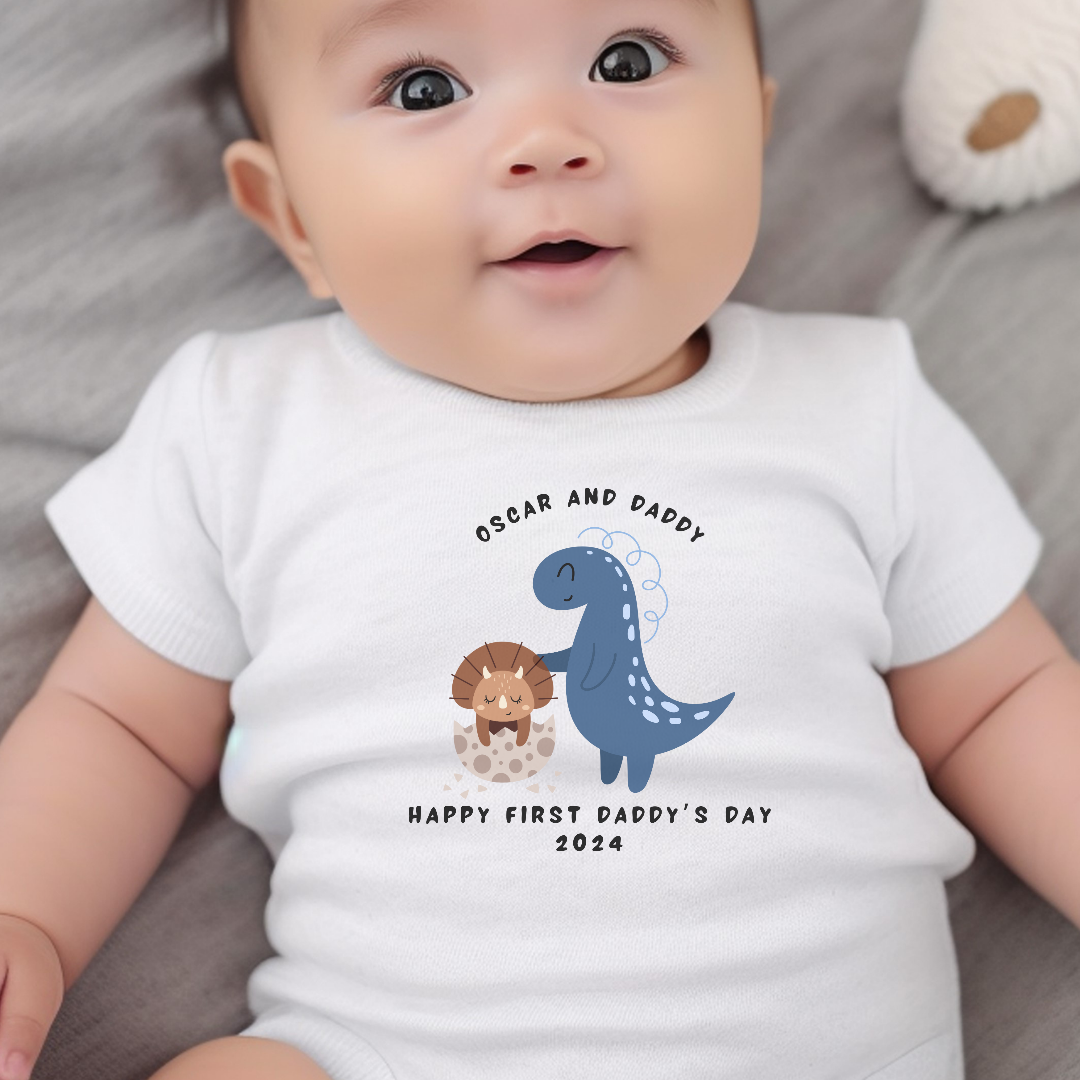 Personalised first fathers day dinosaur baby outfit in white cotton presented in a gift box