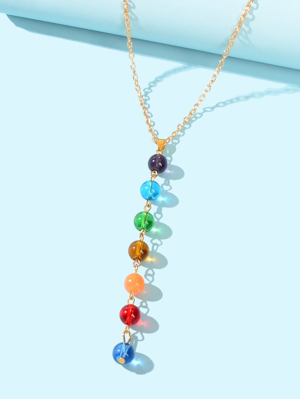 Dainty gold chain Y-shape lariat necklace with colorful glass beads on a female neckline — view 3
