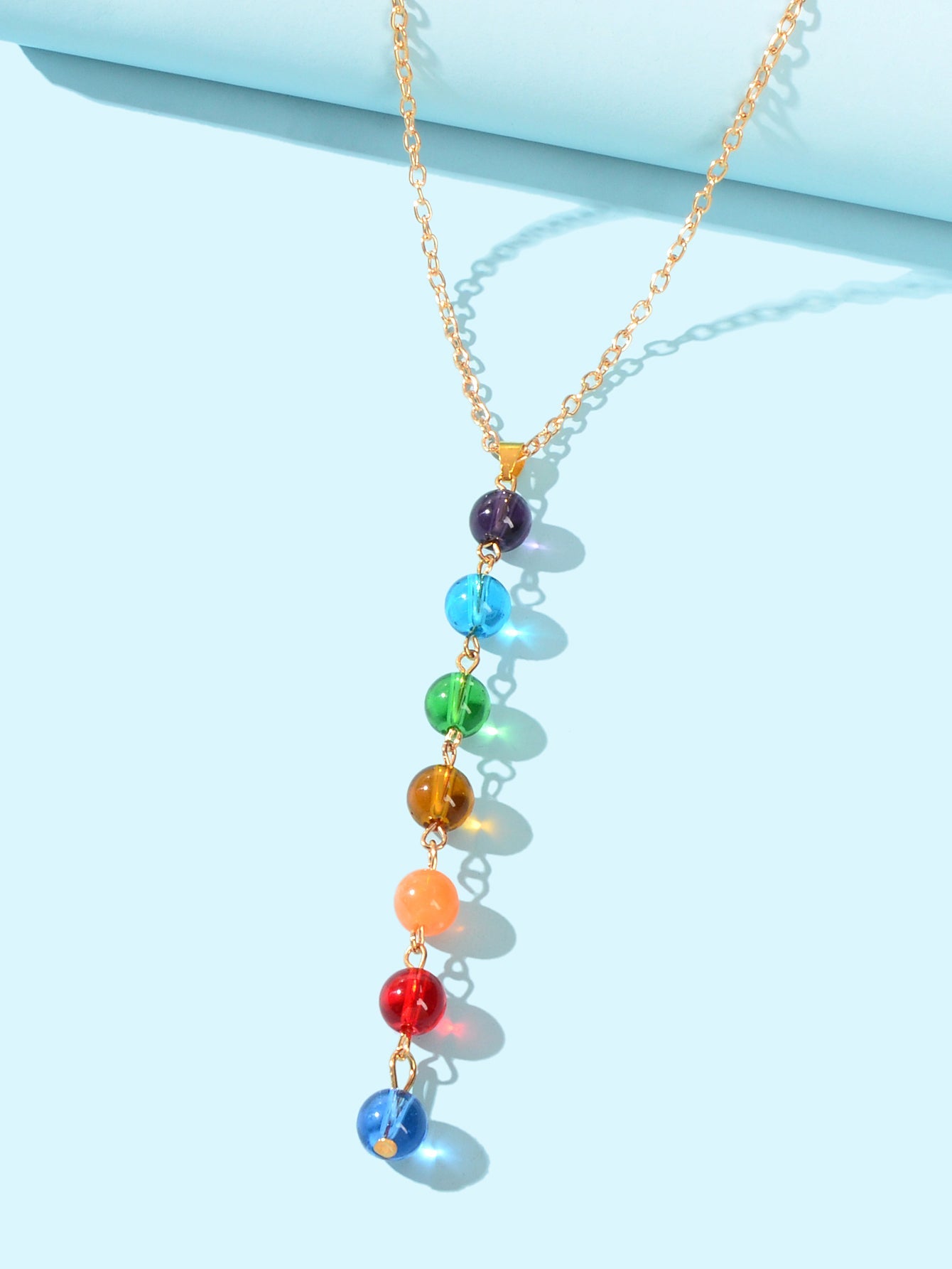 Dainty gold chain Y-shape lariat necklace with colorful glass beads on a female neckline — view 3